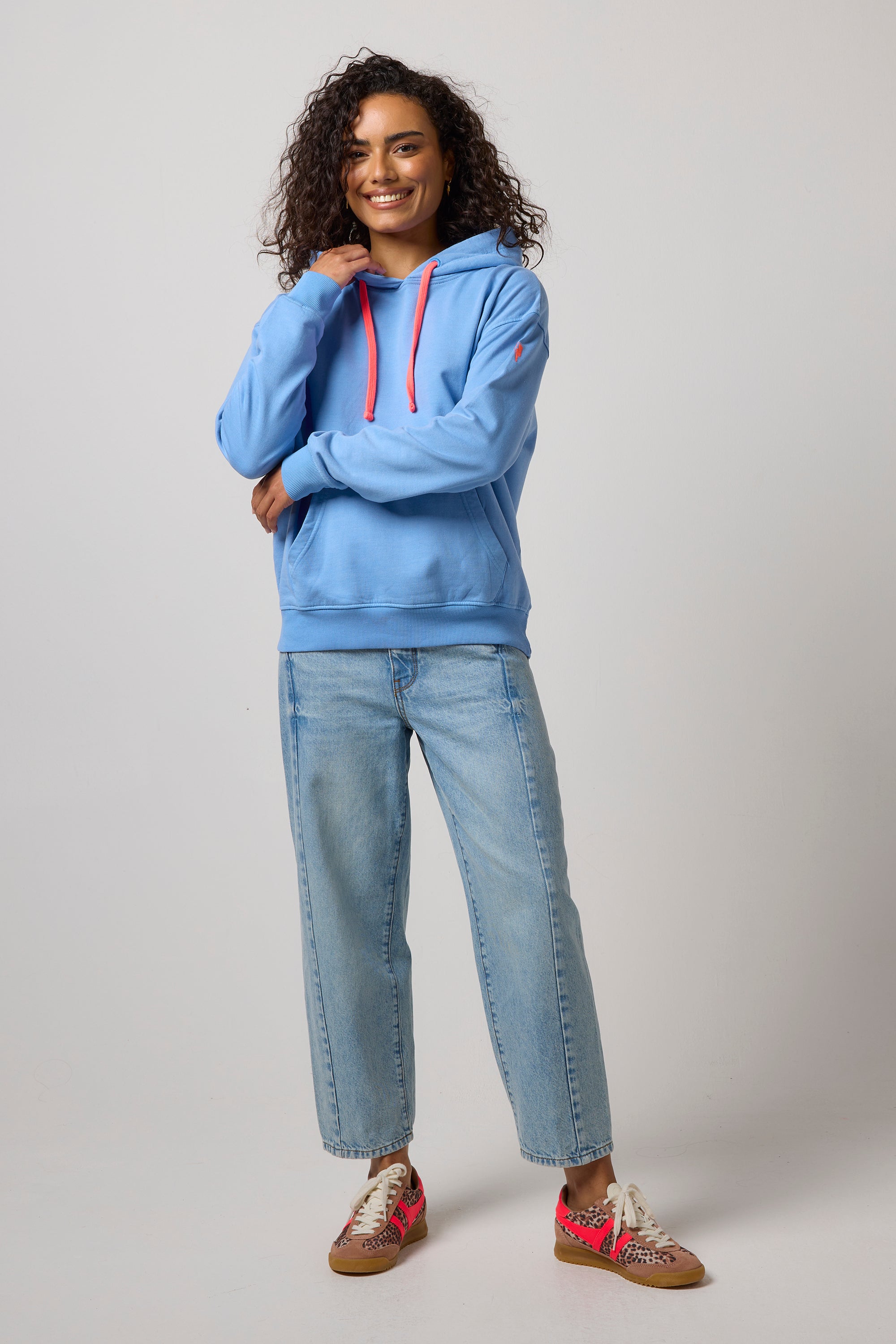 Scamp & Dude Blue Washed Ultimate Hoodie | Model wearing a light blue hoodie with red drawstrings, paired with light-wash jeans and neutral cheetah trainers.