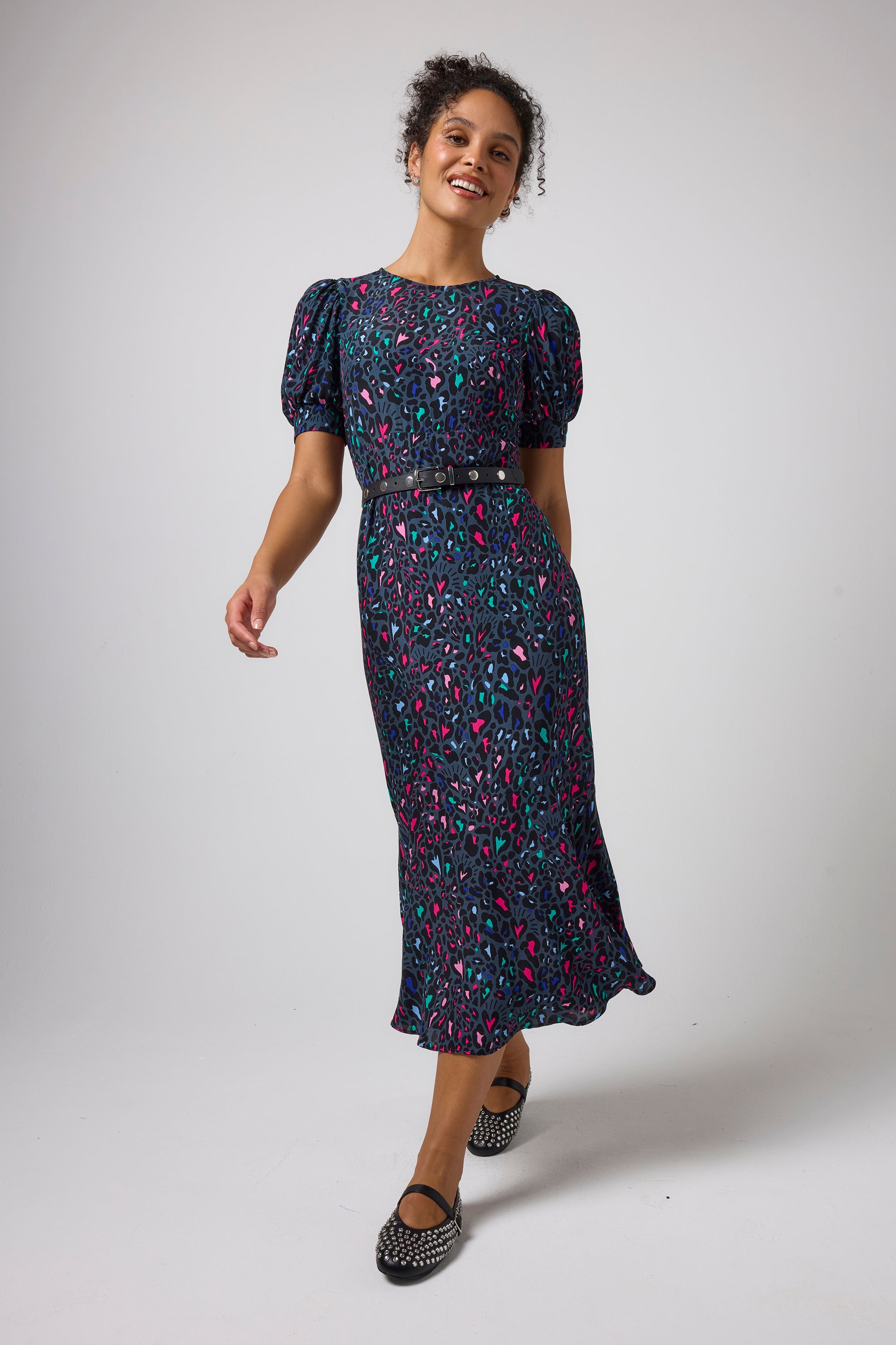Scamp & Dude Grey Love Leopard Midi Dress | Model wearing a grey love leopard print dress with a puff sleeve and studded black pumps.