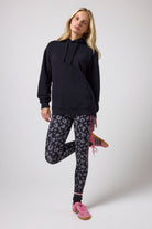 Scamp & Dude Black Multi Neon Bolt Longline Hoodie | Model wearing a black hoodie and patterned leggings on a white background.