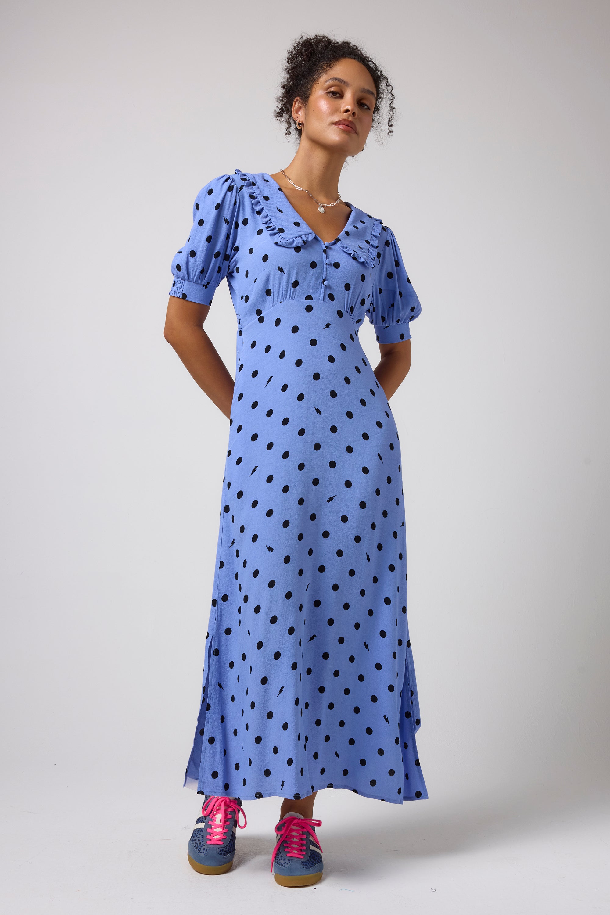 Scamp & Dude Blue with Black Polka Dot Bolt Collared Midi Tea Dress | Model wearing a light blue midi dress with black polka dots, featuring short puff sleeves and a ruffled collar.