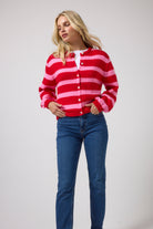 Scamp & Dude Red with Pink Stripe Cardigan | Model wearing a red and pink striped button-up cardigan with blue jeans.