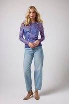 Scamp & Dude Blue Tiger Moth Mesh Top | Model wearing a mesh tiger mosh print top with a pair of light blue jeans.