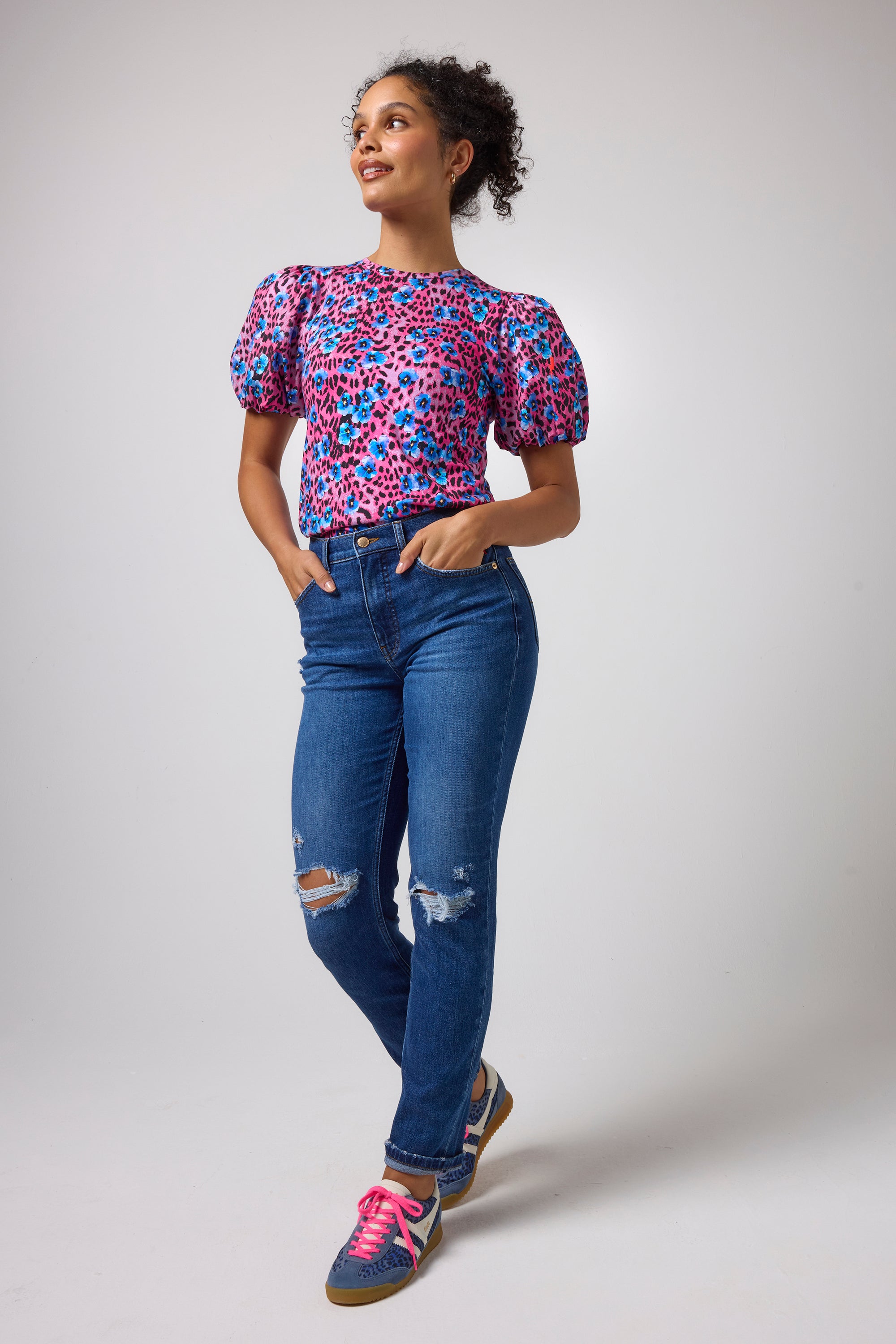 Scamp & Dude Pink Paradise Cheetah Puff Sleeve T-Shirt | Model wearing a short-sleeve floral print top with puff sleeves and blue distressed boyfriend jeans.