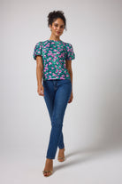 Scamp & Dude Turquoise Paradise Cheetah Puff Sleeve T-Shirt | Model wearing a short-sleeve floral print top with puff sleeves and blue boyfriend jeans.