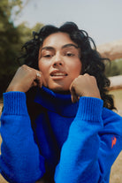 Scamp & Dude Bright Blue Turtleneck Knitted Jumper | Model wearing a bright royal blue knit turtleneck sweater, posing outdoors.