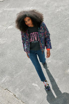 Scamp and Dude Grey with Rainbow Shadow Leopard Short Puffer Coat | Model wearing blue jeans with a dark grey love sweatshirt and a grey rainbow leopard puffer coat.
