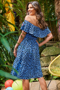 The back of a brunette lady wearing a soft blue with black floral leopard and lightning bolt short Bardot dress