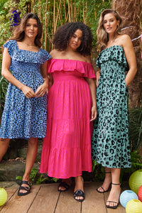 A lady wearing a khaki with black leopard print midi Bardot dress with two other women also wearing bardot dresses