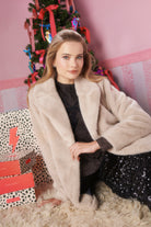 Scamp and Dude Cream Faux Fur Coat | Model wearing a lurex knit jumper with a sequin skirt and cream faux fur jacket.