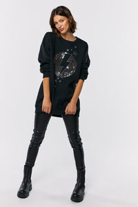 Scamp and Dude Black with Sequin Lightning Bolt Oversized Tunic | Model wearing back sweatshirt with sequin lightening bolt in a moon design with leather trousers and black boots