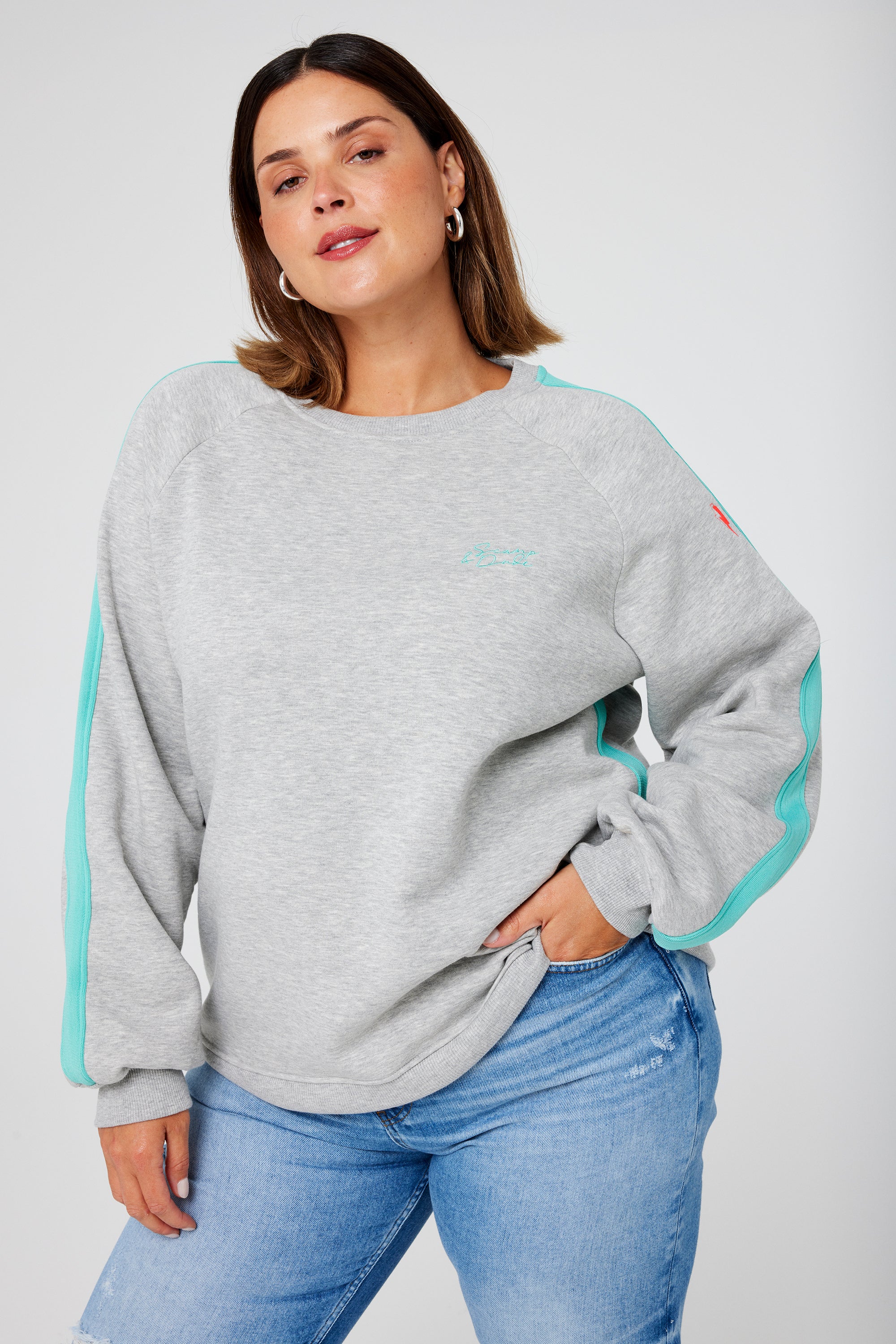 Scamp and Dude Grey Marl with Turquoise Colourblock Oversized Sweatshirt | Model wearing blue jeans with an oversized grey sweatshirt that features a turquoise colourblock detail on the sleeve and seam.