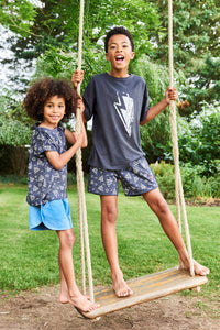 Two boys standing up on a swing wearing Scamp & Dude T-shirts and shorts