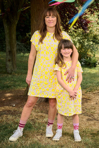 A woman and a child wearing matching blush with neon yellow leopard and lightning bolt T-shirt dresses