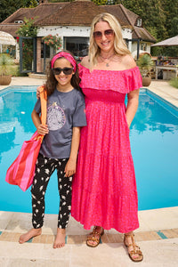 Jo wearing a magenta with hot pink floral leopard  bardot midi dress poolside with a child wearing a Scamp & Dude outfit