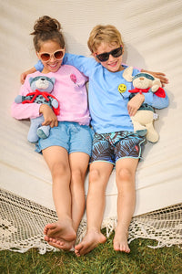 Two children with their arms round each other wearing Scamp & Dude outfits holding Scamp & Dude sleep buddies