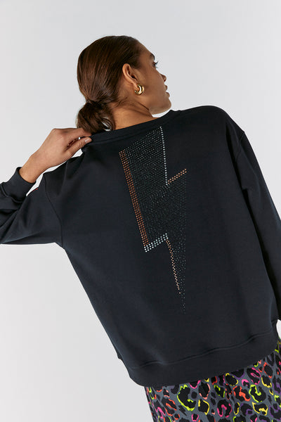Scamp and Dude Washed Black with Studded Lightning Bolt Oversized Sweatshirt | Model with back the camera wearing a sweatshirt with a glitter lightening bolt on the back