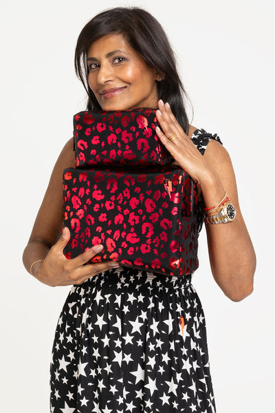Scamp and Dude x Ruby Hammer Black with Red Foil Leopard Cosmetic Bag | Ruby Hammer holding two different sized red leopard bags wearing a black and white star printed dress 