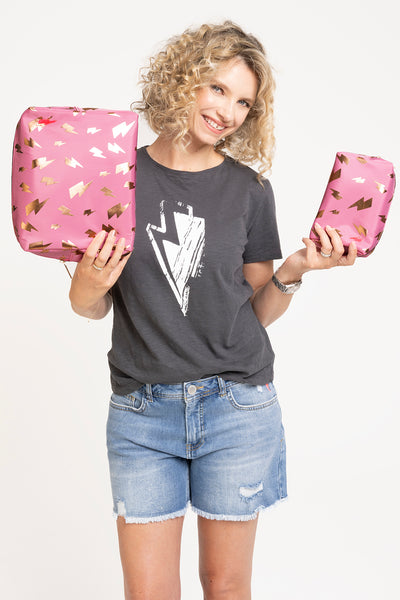 Scamp and Dude x Ruth Crilly Pink with Rose Gold Foil Lightning Bolt Cosmetic Bag | Ruth Crilly holding two pink cosmetics bags wearing a grey top and denim shorts