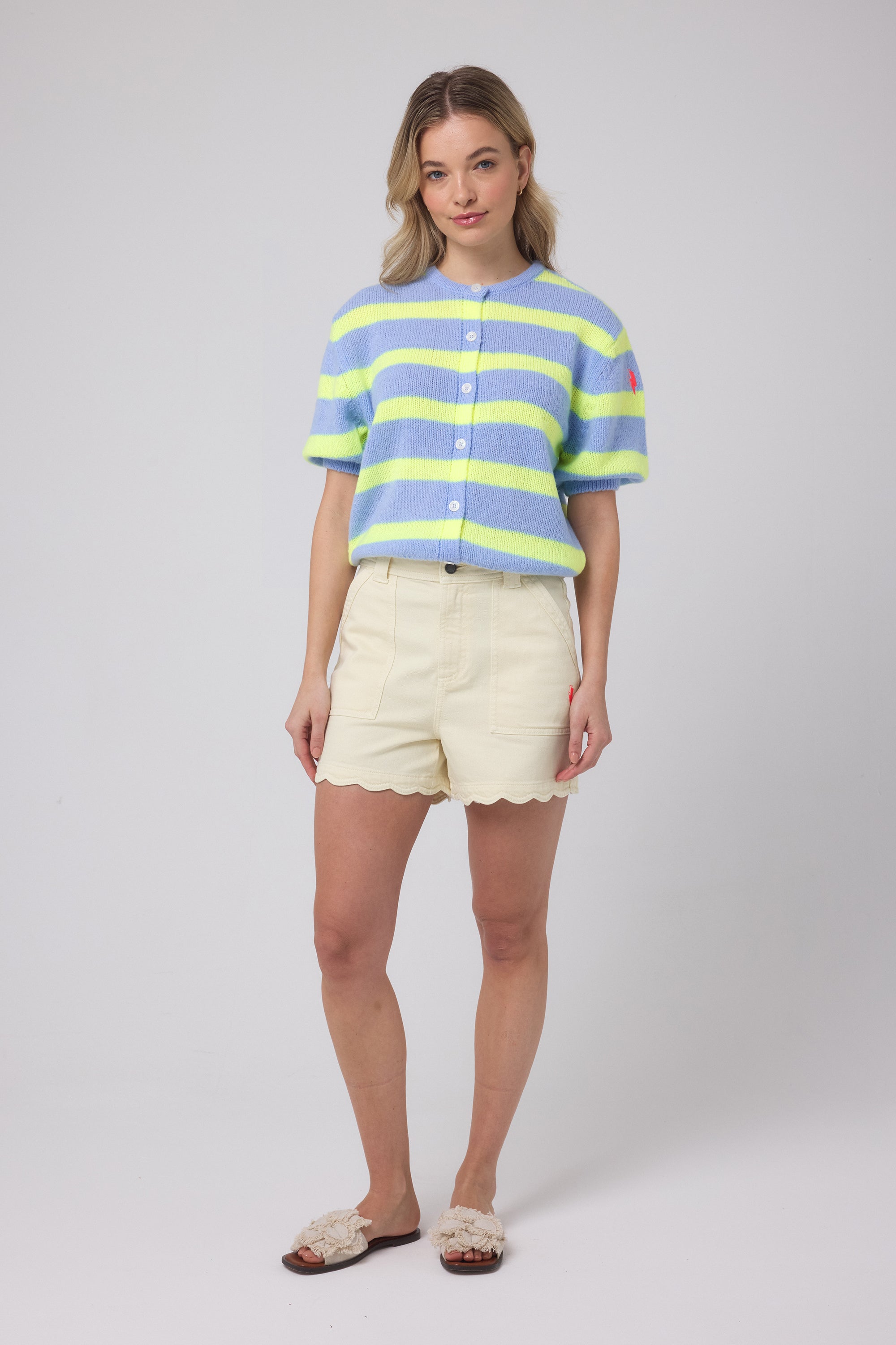 Scamp and Dude Light Blue with Yellow Stripe Short Sleeve Cardigan | Model wearing a pale blue and yellow stripe short sleeve cardigan with a pair of yellow scallop denim shorts.