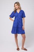 Scamp and Dude Blue V-Neck Broderie Short Dress | Model wearing a short v-neck broderie dress with brown flat sandals.