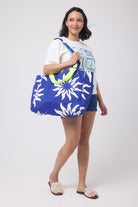 Scamp and Dude Blue with Cream Wiggle Sunstar Reversible Beach Bag | Model wearing a pair of blue denim shorts with a graphic print t-shirt, holding a reversible beach bag with sun print.
