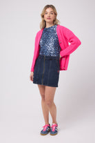 Scamp and Dude Dark Indigo Zip Front Denim Mini Skirt | Model wearing a dark indigo denim mini skirt with zip front detail. Worn with a navy cheetah print t-shirt and neon pink cardigan.