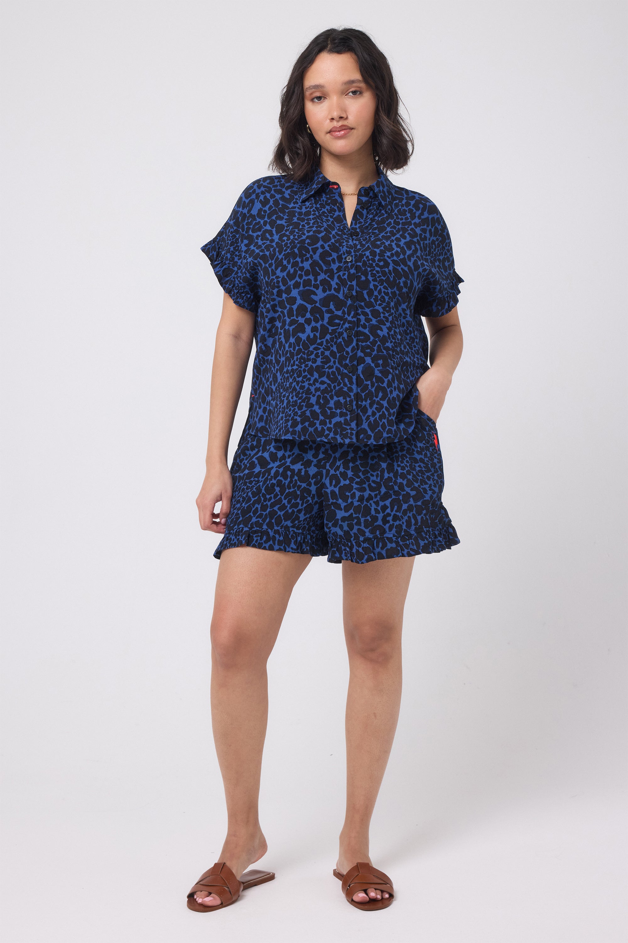 Scamp and Dude Navy with Black Rock and Roll Leopard Frill Sleeve Shirt | Model wearing a navy leopard print shirt and matching shorts with flat brown sandals.