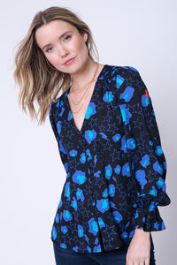 A lady wearing a tucked in black top with blue snow leopard, star and lightning bolt print with dark indigo jeans