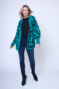 A lady wearing a teal with black zebra chunky knitted cardigan with Scamp & Dude branded buttons over a black t-shirt