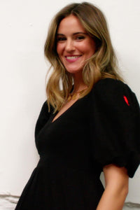 A lady wearing a black v-neck shirred dobby maxi dress with puff sleeves