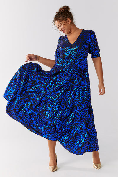 Scamp and Dude Black with Blue Foil Leopard Maxi Dress | Model smiling wearing shiny blue long dress with gold heeled shoes