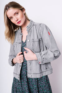 Scamp and Dude Washed Grey Short Frill Collar Denim Jacket | Model with blonde hair wearing a light wash grey denim jacket with both hands placed on buttons