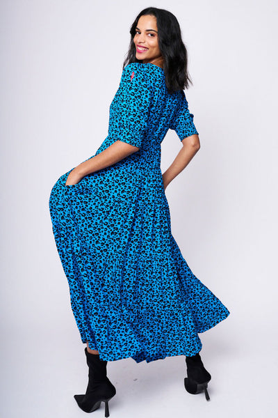 Scamp and Dude Electric Blue Leopard Tiered Maxi Dress | Model smiling wearing blue leopard print long dress with black high heeled boots