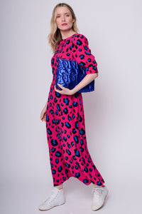 A lady in a pink with blue & black snow leopard dress holding a metallic electric blue swag bag with quilted lightning bolts
