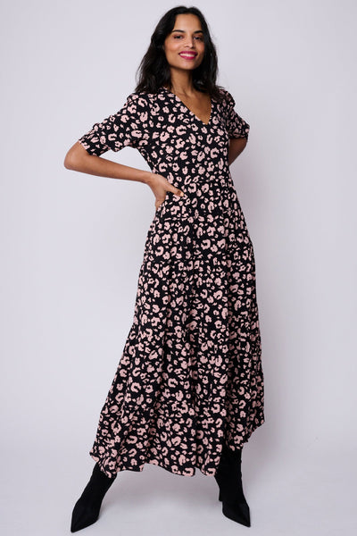 A lady wearing a black v-neck maxi dress with pale peach leopard and lightning bolt print, the dress has short puffed sleeves