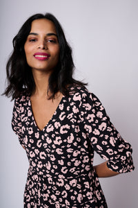 A lady wearing a black v-neck maxi dress with pale peach leopard and lightning bolt print, the dress has short puffed sleeves