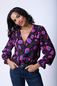 A lady wearing a button down magenta and blue snow leopard, star and lightning bolt print top