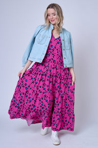 A lady wearing a magenta V-neck maxi dress with blue and black snow leopard & star print with a pale blue denim jacket