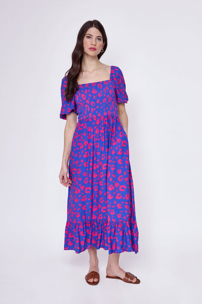 A lady wearing an electric blue with hot pink leopard and lightning bolt print shirred midi dress with pretty blouson sleeves