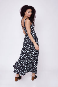 A lady looking over her shoulder wearing a black with white star & lightning bolt print maxi sundress and block heel sandals