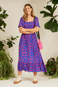 A lady wearing an electric blue with hot pink leopard and lightning bolt print shirred midi dress with pretty blouson sleeves