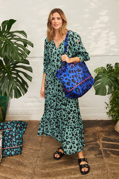 A lady in a Scamp & Dude dress carrying a blue with black leopard and lightning bolt print Weekender bag over her shoulder