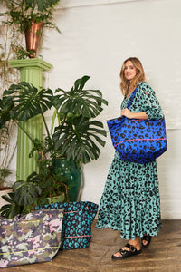 A lady in a Scamp & Dude dress carrying a blue with black leopard and lightning bolt print Weekender bag over her shoulder
